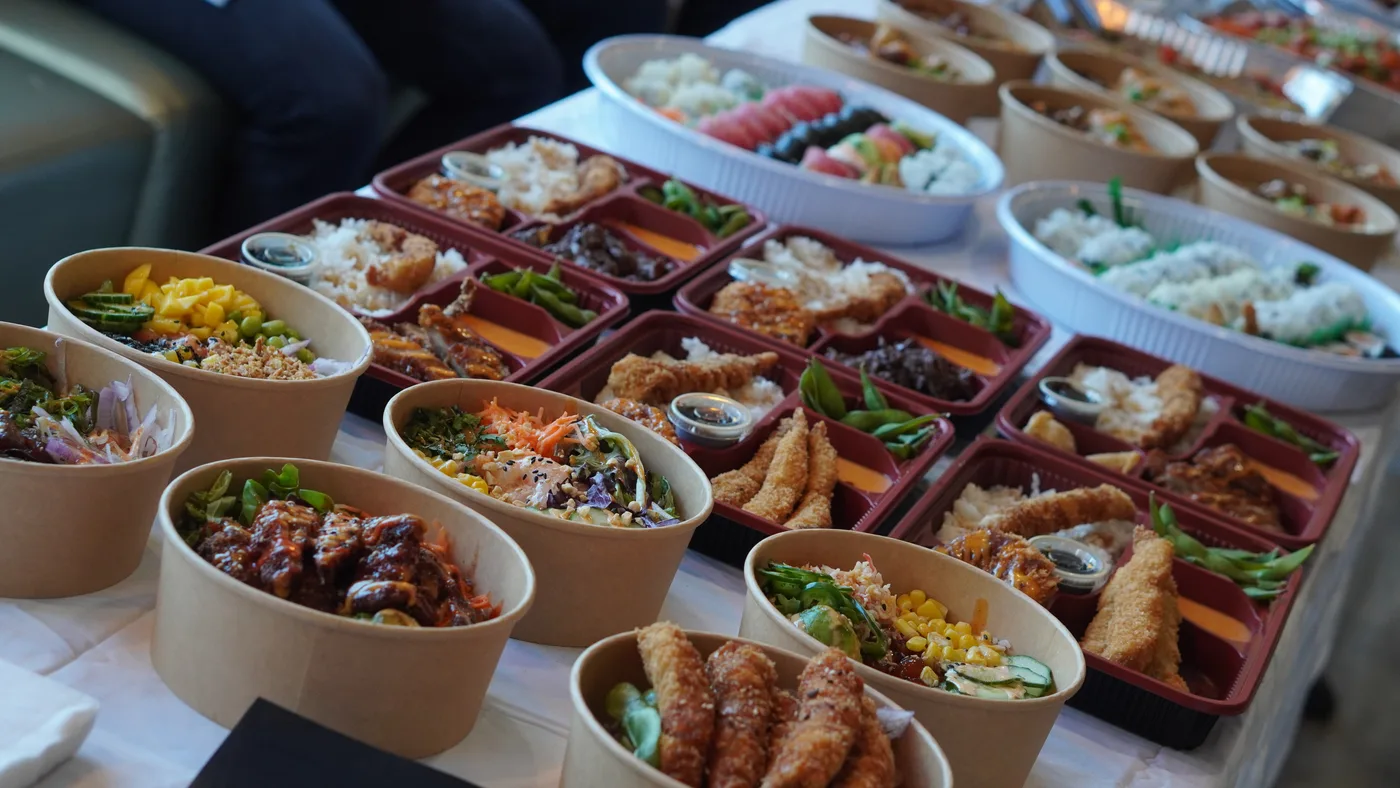 A catering table of rice bowls, bento trays and sushi platters