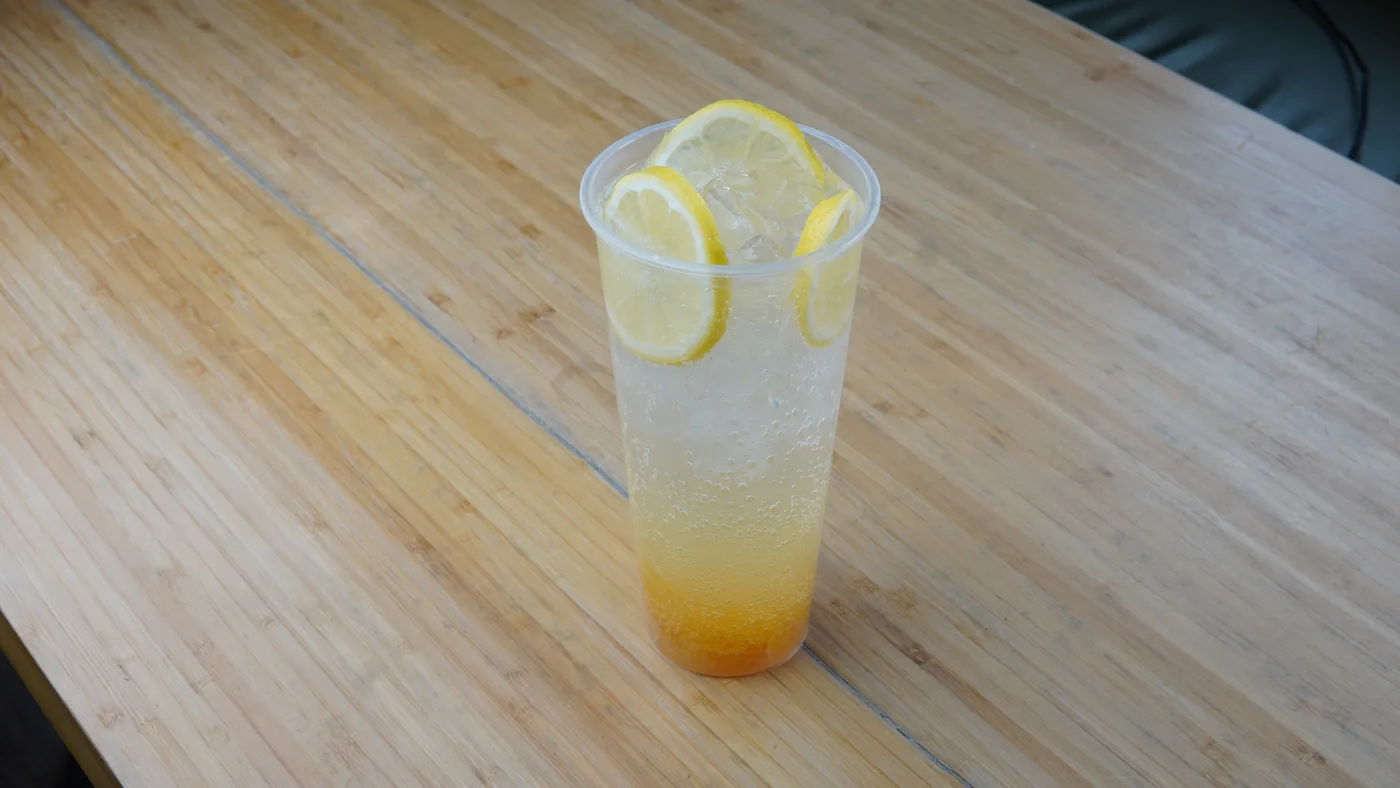 A glass of sparkling yuzu ade with lemon slices